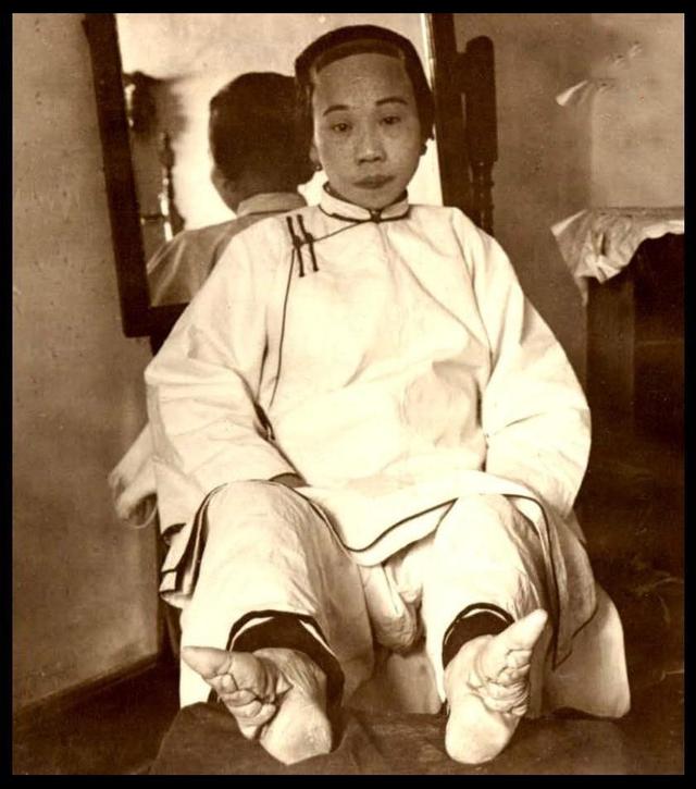 本图为上色之后的老照片,女人裹脚再加上清朝特有的"高跟鞋".