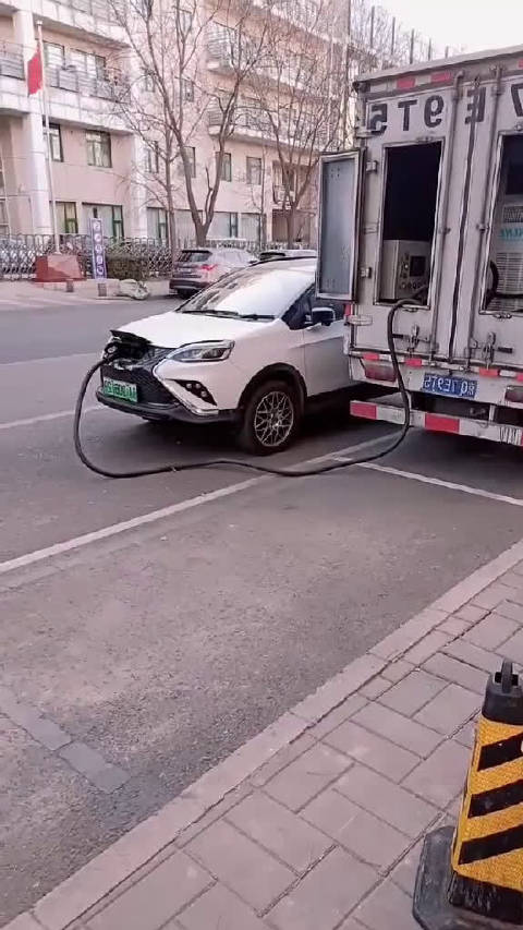 开着烧油的车拉着电瓶给没电的电动车去充电！