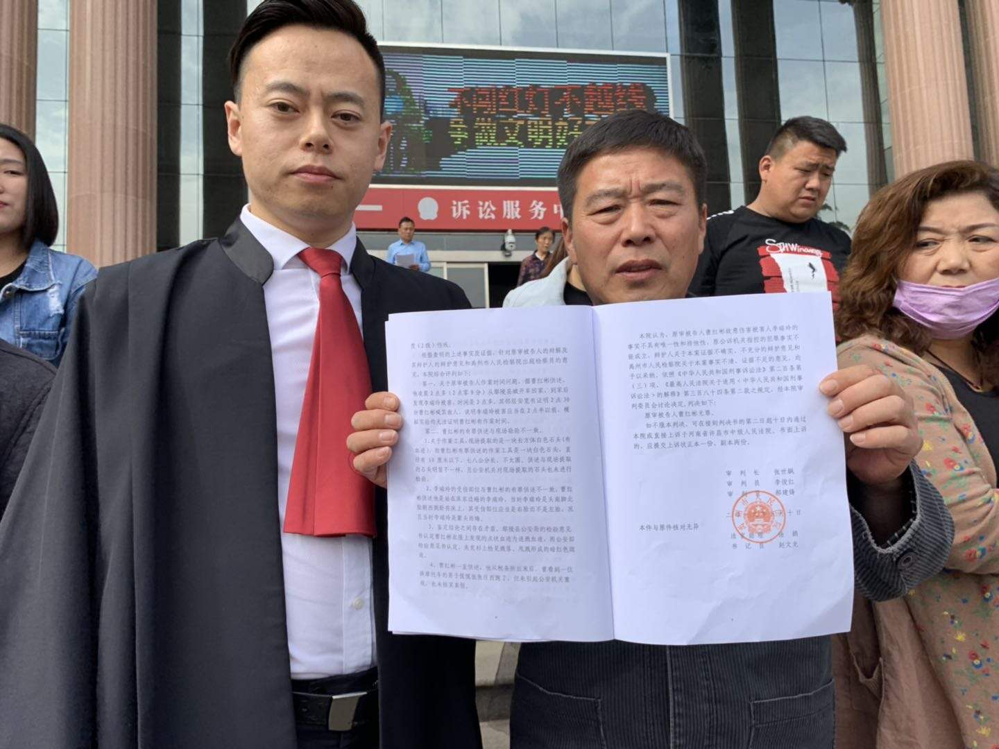 5月13日下午,曹红彬被宣布无罪后,举着判决书与辩护律师合影。本文图片均由受访者提供