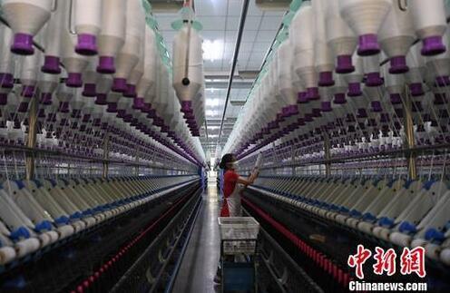 资料图:一家纺织厂工人在生产车间作业。中新社记者 张斌 摄