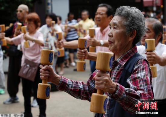 资料图：当地时间2014年9月15日，日本东京巢鸭区，日本老人们手持木质哑铃齐跳“广场舞”宣传健康活动以此庆祝敬老日的到来。