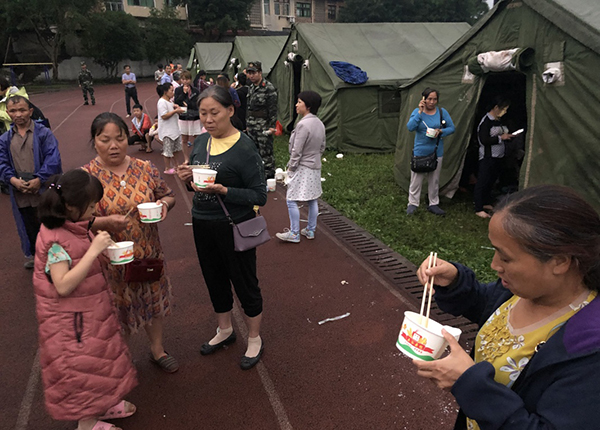  6月18日，在长宁县双河镇中学操场，群众吃上热粥。新华社 图