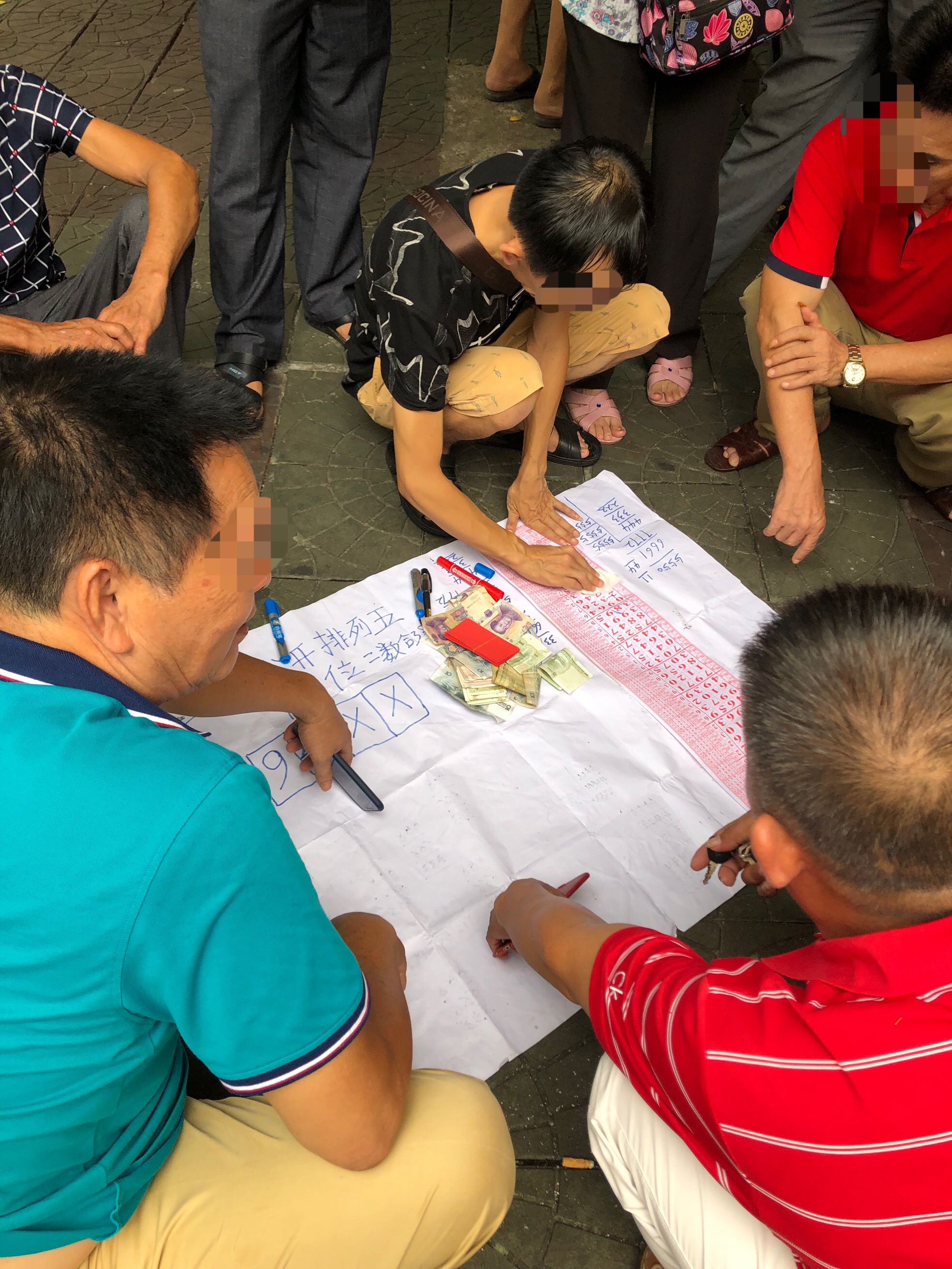 7月12日,海口市琼山区三角公园内,多名私彩玩家聚在一起听“码师”分析私彩中奖规律。新京报记者 吴江 摄