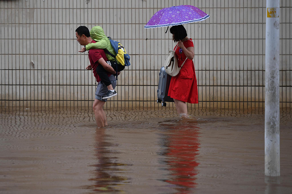  2019年7月20日，昆明，市民小心走过积水路段。视觉中国 图