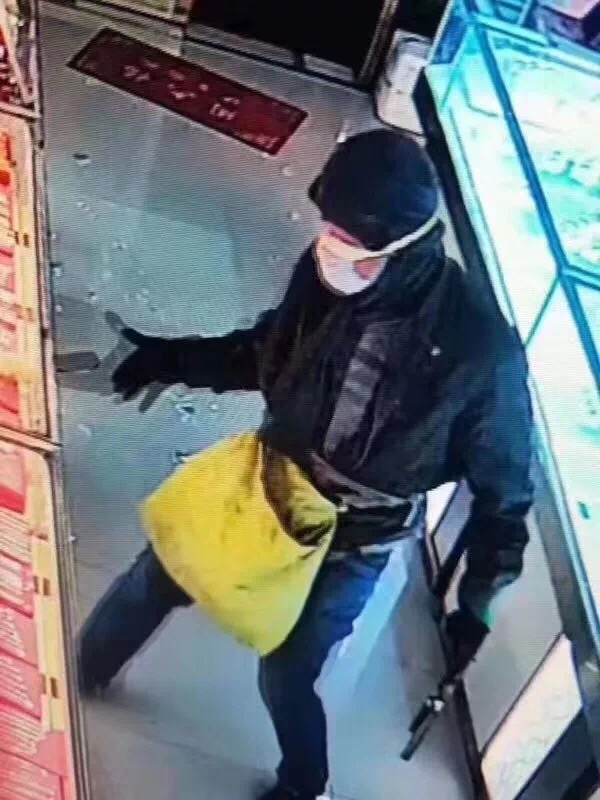 另一名疑持枪男子腰间跨黄色袋子，将玻璃砸碎后将金饰拿出。受访者供图