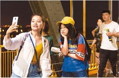 时下，哈尔滨市正值暑期旅游旺季，夜色中“老江桥”附近游人如织。图为游客们正在“老江桥”上自拍。 谢剑飞摄 新华社发