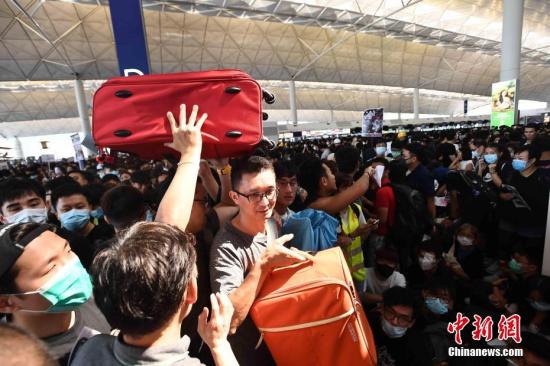 8月12日下午三时许,大批非法集结于香港国际机场的示威者拆走铁马,进入原先只限持机票旅客才可进入的离境大堂禁区前通道位置。受非法集结影响,大批登机旅客受阻,航班取消。中新社记者 麥尚旻 摄