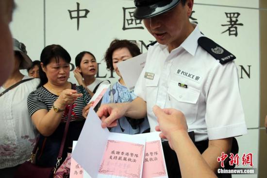 8月10日，“守护香港大联盟”当天在香港各区发起“全民撑警日”活动。资料图为市民将慰问卡及签发递交中区警署值日警官。中新社记者 洪少葵 摄