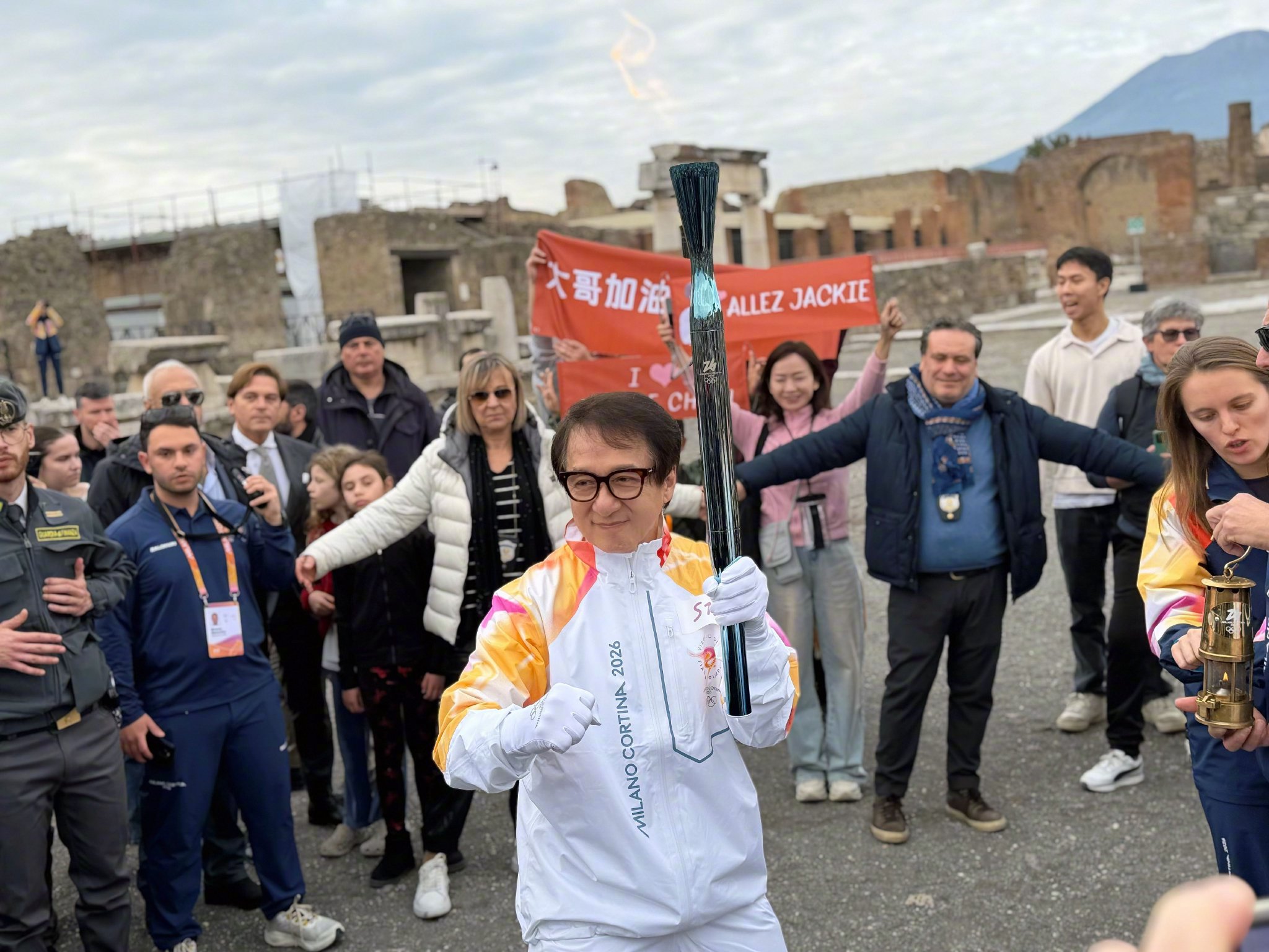 成龙庞贝古城传递冬奥火炬，手持熊猫玩偶展中国文化