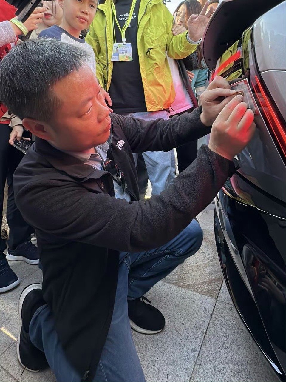 何小鹏蹲下为老车主贴24K金标