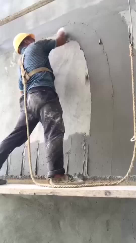 劳动创造财富实拍男子系着安全带批灰