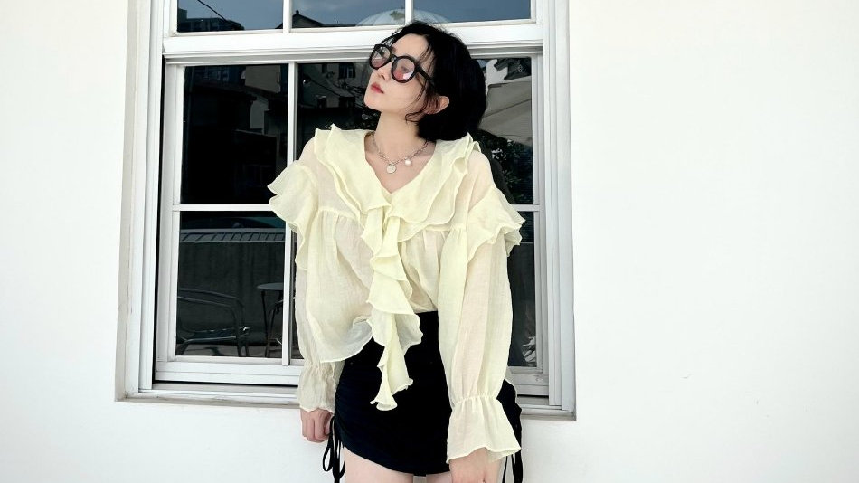 陈小纭身穿米黄色上衣，下搭黑色短裤，可爱满分。