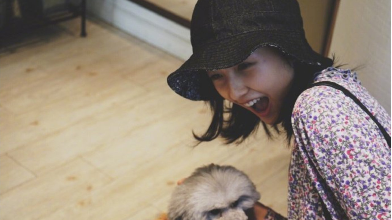 张子枫身穿紫色碎花上衣，戴渔夫帽背双肩包