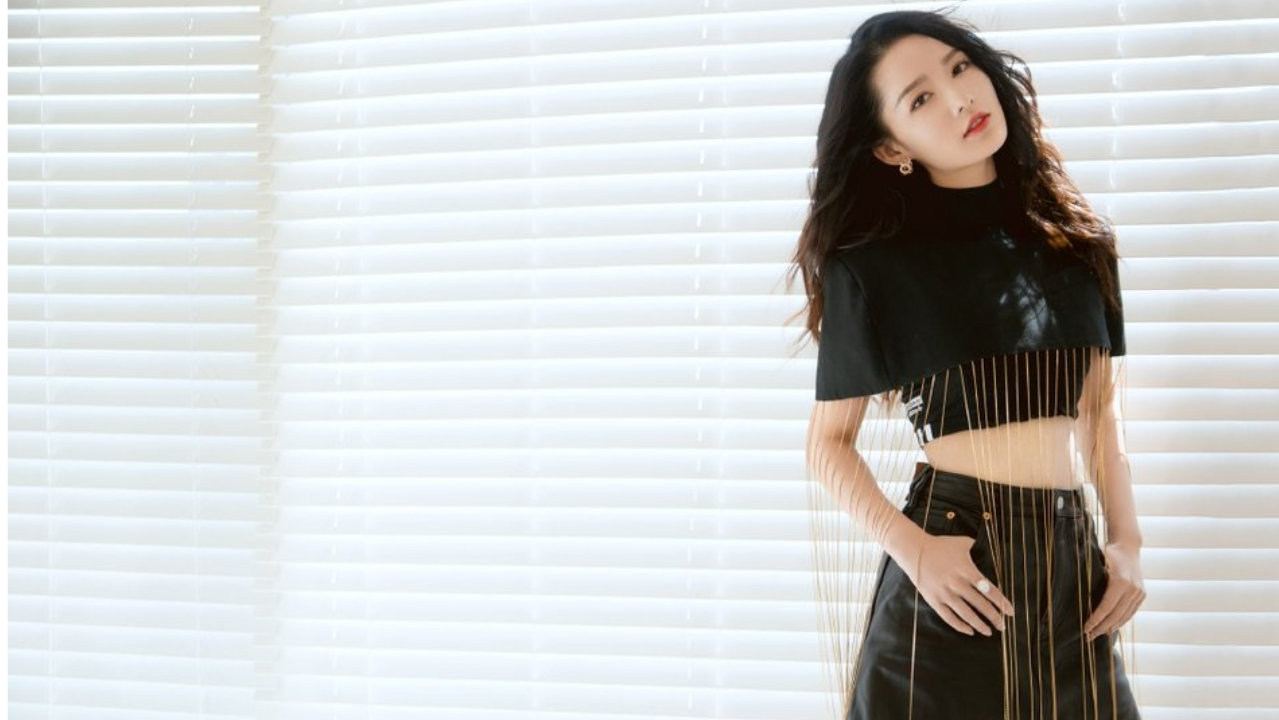 李沁身着黑色金属流苏肩装，配同色皮质短裙大秀长腿