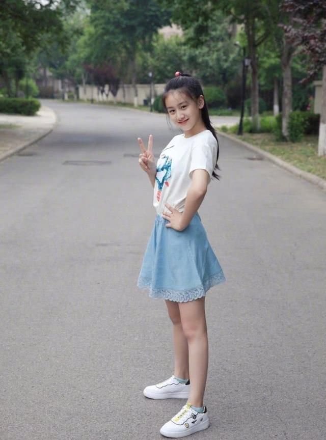坐在滑板上的森碟乖巧可爱,腿前伸放平,鞋子上的卡通图案亮眼,又给她