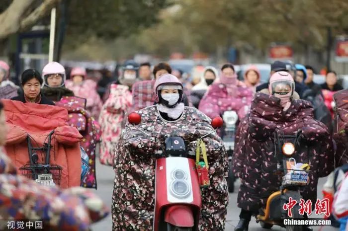 资料图:冷空气来临,行人“全副武装”出行。图片来源:视觉中国