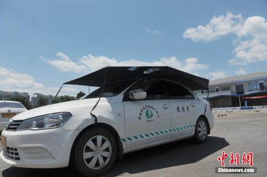 資料圖:一家駕校內,學員在車頂架着遮陽蓬的教練車內練習。 中新社發 胡劍歡 攝 圖片來源:CNSPHOTO
