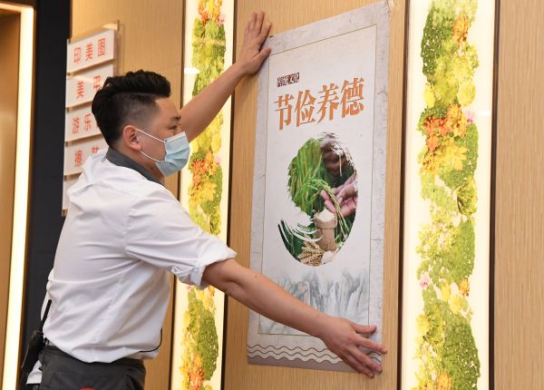 中国向“舌尖上的浪费”说不。图为8月20日,北京一家餐厅的员工张贴“节俭养德”宣传海报。(任超 摄)