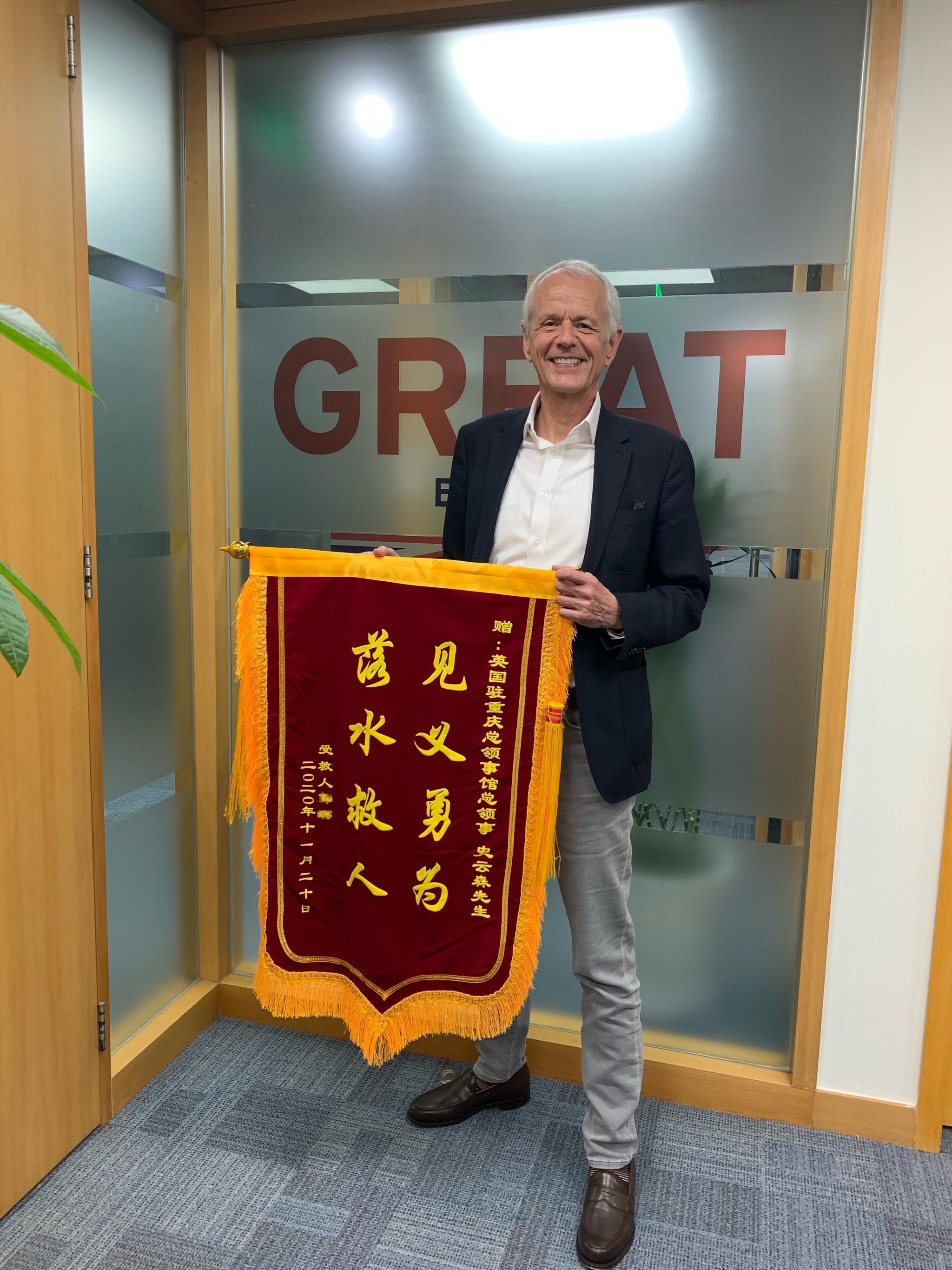 史云森和他收到的锦旗。 英国驻重庆总领事馆供图