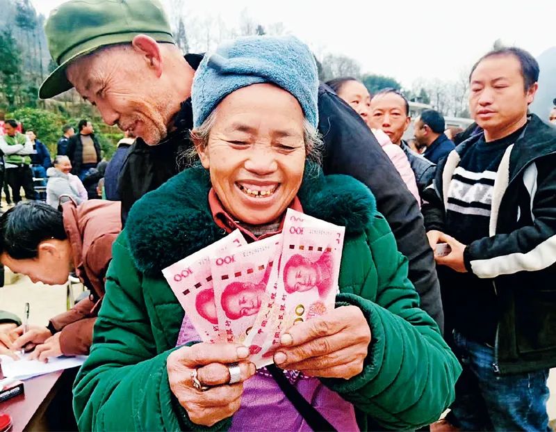▲2020年1月23日农历除夕前一天,在贵州省毕节市纳雍县董地乡扶贫产业分红大会上,一位村民领到分红款后笑逐颜开。图源:新华社