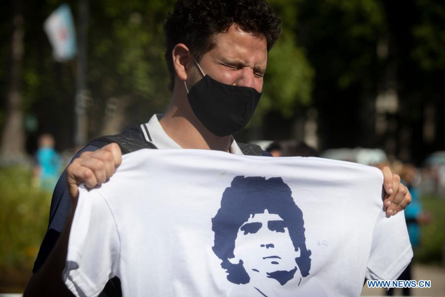 A fan holding a shirt with the image of Maradona waits outside the funeral chapel of football legend Diego Maradona at the Casa Rosada in Buenos Aires, capital of Argentina, Nov. 26, 2020. Maradona died at the age of 60 on Wednesday of a heart attack. (Photo by Martin Zabala/Xinhua)