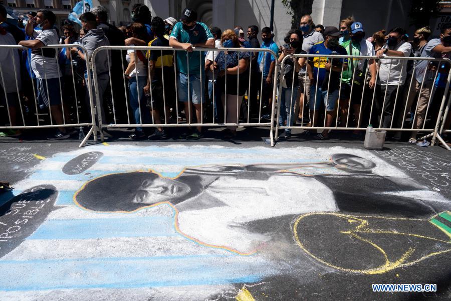 Fans wait outside the funeral chapel of football legend Diego Maradona along a chalk drawing of Maradona at the Casa Rosada in Buenos Aires, capital of Argentina, Nov. 26, 2020. Maradona died at the age of 60 on Wednesday of a heart attack. (Photo by Martin Zabala/Xinhua)