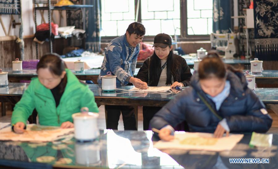 Wang Fangzhou (2nd L) guides a tourist in drawing batik patterns at a batik experience gallery in Danzhai County of Guizhou Province in southwest China, Dec. 1, 2020. Wang Fangzhou, 40, started in August 2016 a workshop specialized in batik, a craft inherited through generations among the Miao ethnic group in Guizhou. Later on, he launched a batik experience gallery in Wanda Township, a local tourist attraction. His workshop and gallery have received more than 6,000 tourists so far this year with combined sales revenue of over 300,000 yuan (about 45,500 U.S. dollars). Thirteen residents relocated from poverty-stricken areas have found employment with decent salaries here. (Xinhua/Yang Ying)