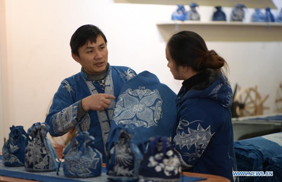 Wang Fangzhou (L) explains a batik product to a sales assistant at a batik workshop in Danzhai County of Guizhou Province in southwest China, Dec. 1, 2020. Wang Fangzhou, 40, started in August 2016 a workshop specialized in batik, a craft inherited through generations among the Miao ethnic group in Guizhou. Later on, he launched a batik experience gallery in Wanda Township, a local tourist attraction. His workshop and gallery have received more than 6,000 tourists so far this year with combined sales revenue of over 300,000 yuan (about 45,500 U.S. dollars). Thirteen residents relocated from poverty-stricken areas have found employment with decent salaries here. (Xinhua/Yang Ying)