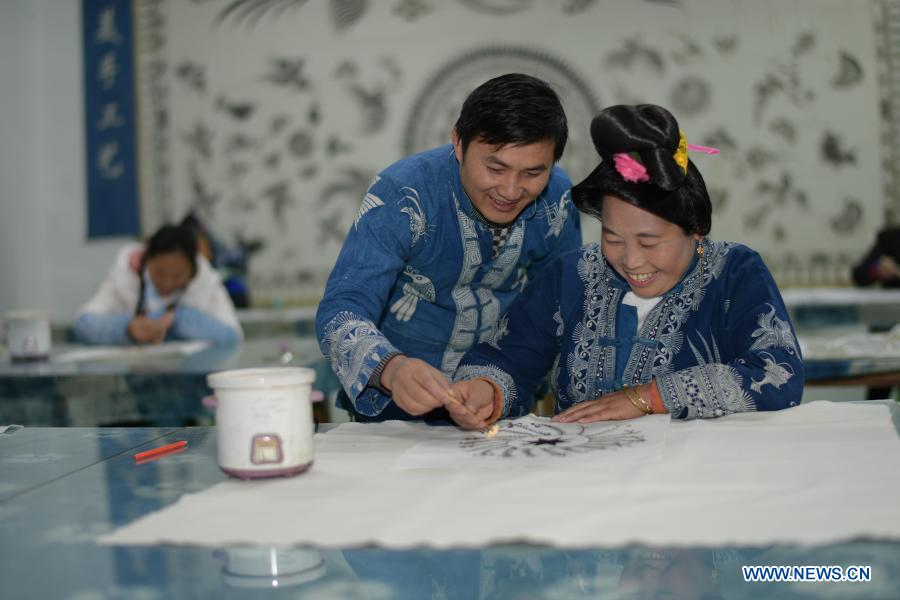 Wang Fangzhou (L) guides a female worker relocated from poverty-stricken area in drawing batik patterns at a batik workshop in Danzhai County of Guizhou Province in southwest China, Dec. 1, 2020. Wang Fangzhou, 40, started in August 2016 a workshop specialized in batik, a craft inherited through generations among the Miao ethnic group in Guizhou. Later on, he launched a batik experience gallery in Wanda Township, a local tourist attraction. His workshop and gallery have received more than 6,000 tourists so far this year with combined sales revenue of over 300,000 yuan (about 45,500 U.S. dollars). Thirteen residents relocated from poverty-stricken areas have found employment with decent salaries here. (Xinhua/Yang Ying)