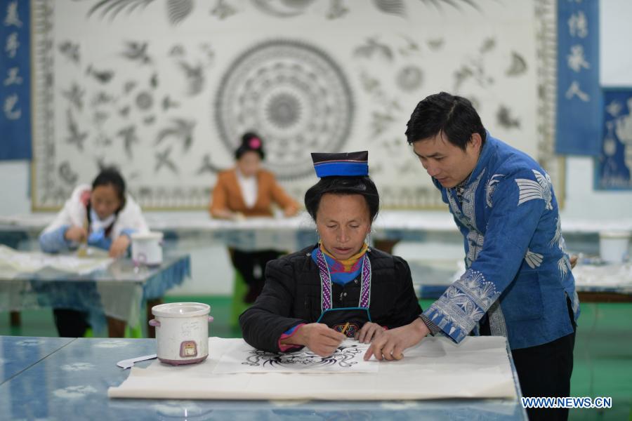 Wang Fangzhou (1st, R) guides a female worker relocated from poverty-stricken area in drawing batik patterns at a batik workshop in Danzhai County of Guizhou Province in southwest China, Dec. 1, 2020. Wang Fangzhou, 40, started in August 2016 a workshop specialized in batik, a craft inherited through generations among the Miao ethnic group in Guizhou. Later on, he launched a batik experience gallery in Wanda Township, a local tourist attraction. His workshop and gallery have received more than 6,000 tourists so far this year with combined sales revenue of over 300,000 yuan (about 45,500 U.S. dollars). Thirteen residents relocated from poverty-stricken areas have found employment with decent salaries here. (Xinhua/Yang Ying)