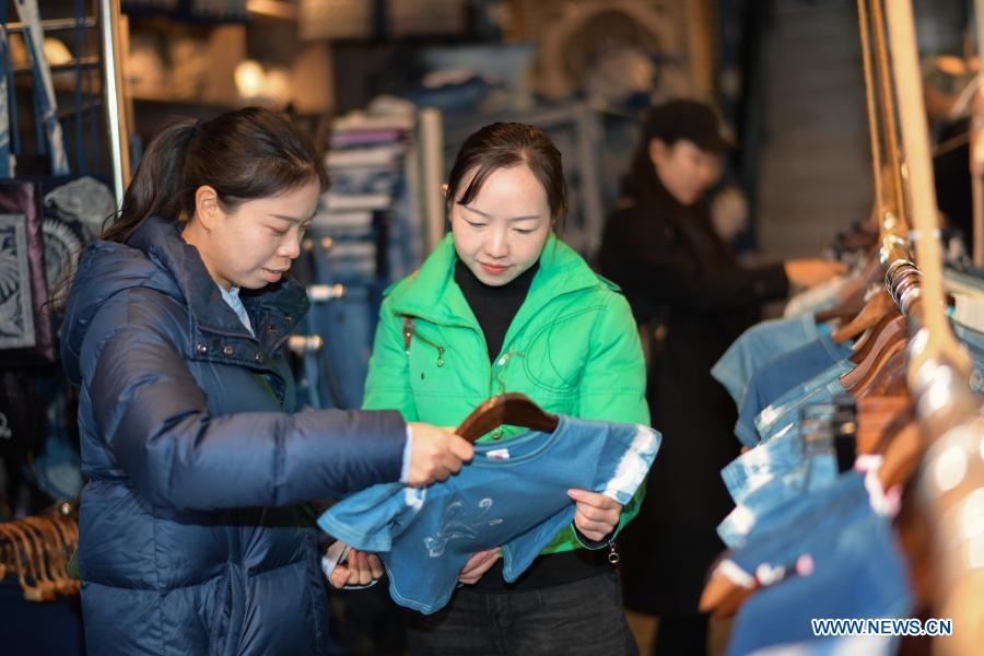 Tourists buy batik products at a batik experience gallery in Danzhai County of Guizhou Province in southwest China, Dec. 1, 2020. Wang Fangzhou, 40, started in August 2016 a workshop specialized in batik, a craft inherited through generations among the Miao ethnic group in Guizhou. Later on, he launched a batik experience gallery in Wanda Township, a local tourist attraction. His workshop and gallery have received more than 6,000 tourists so far this year with combined sales revenue of over 300,000 yuan (about 45,500 U.S. dollars). Thirteen residents relocated from poverty-stricken areas have found employment with decent salaries here. (Xinhua/Yang Ying)