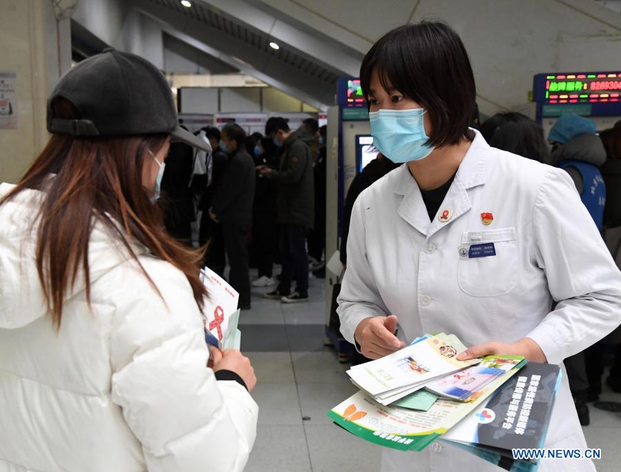 A medical worker (R) hands out AIDS prevention brochures during an AIDS awareness campaign held on the occasion of World AIDS Day at Haidian Hospital in Beijing, capital of China, Dec. 1, 2020. (Xinhua/Ren Chao)