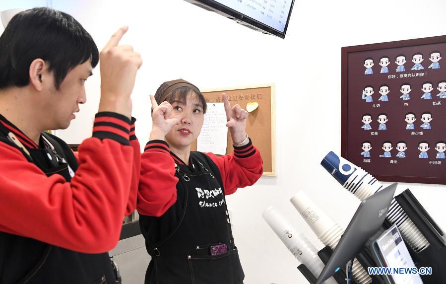 Staff members Li Tao (L) and Cao Ruihua practice sign language in Silence Coffee in Xincheng District of Xi'an, northwest China's Shaanxi Province, Dec. 1, 2020. Silence Coffee, a coffee shop opened in Xi'an more than two months ago, is also a business incubator established for disabled people. Three of the four staff members in Silence Coffee are hearing-impaired baristas. They communicate with customers with sign language or typing on cellphone. Working on two shifts, all four members carried out routine work in the coffee shop including coffee making, baking, guest receiving and cleaning. Wang Lichao, manager of Silence Coffee, has learned sign language so as to better guide and 