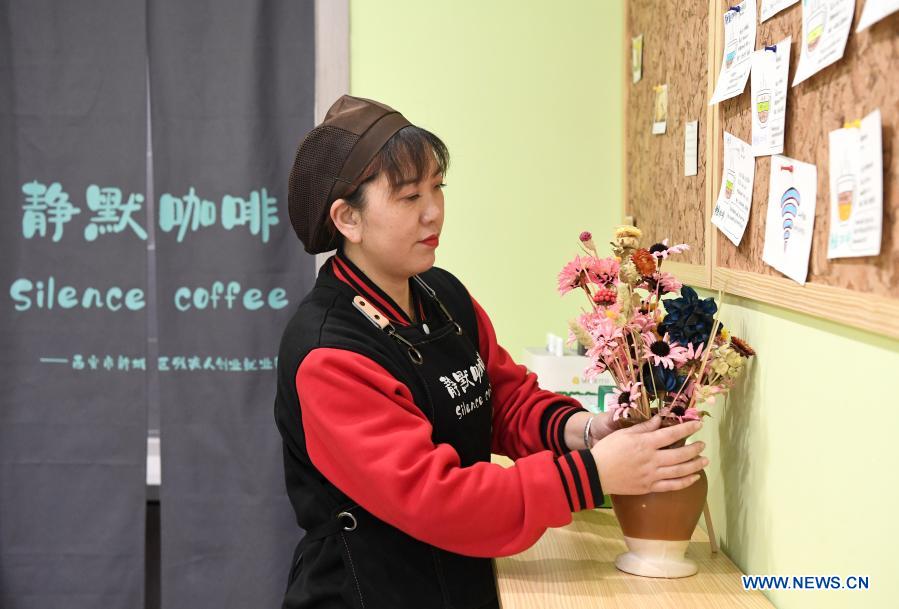 Staff member Cao Ruihua does cleaning work in Silence Coffee in Xincheng District of Xi'an, northwest China's Shaanxi Province, Dec. 1, 2020. Silence Coffee, a coffee shop opened in Xi'an more than two months ago, is also a business incubator established for disabled people. Three of the four staff members in Silence Coffee are hearing-impaired baristas. They communicate with customers with sign language or typing on cellphone. Working on two shifts, all four members carried out routine work in the coffee shop including coffee making, baking, guest receiving and cleaning. Wang Lichao, manager of Silence Coffee, has learned sign language so as to better guide and 