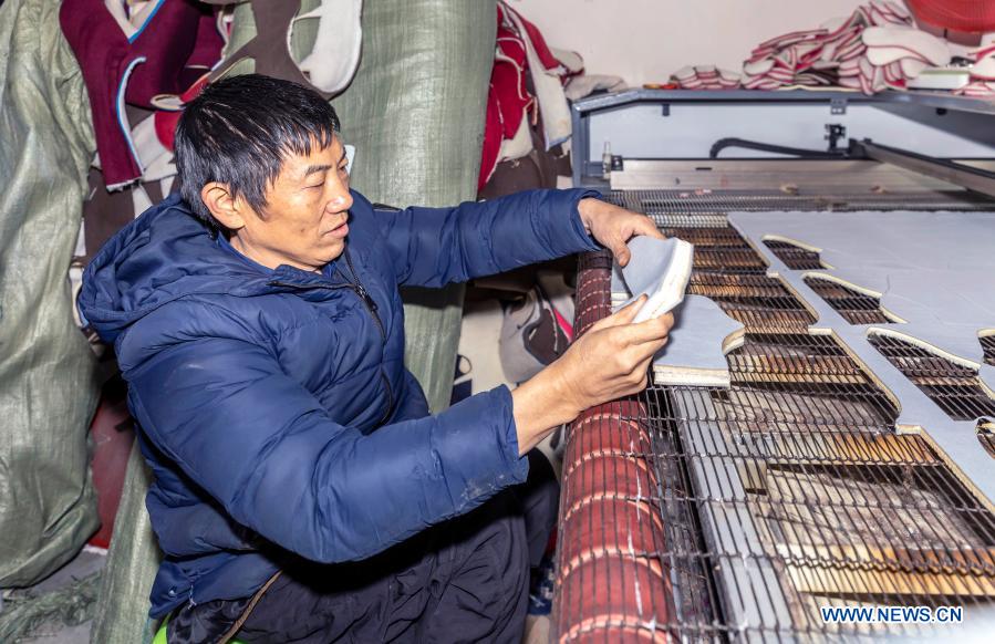 Diao Chaogui, who has disabilities in two legs, makes shoe uppers at his own cotton shoes factory founded in 2017 with local preferential loan specially for impoverished people, in Qianxi County of Bijie City, southwest China's Guizhou Province, Dec. 6, 2020. All 488,000 registered impoverished disabled people in Guizhou had been lifted out of poverty, data from provincial disabled persons' federation showed recently. (Photo by Fan Hui/Xinhua)