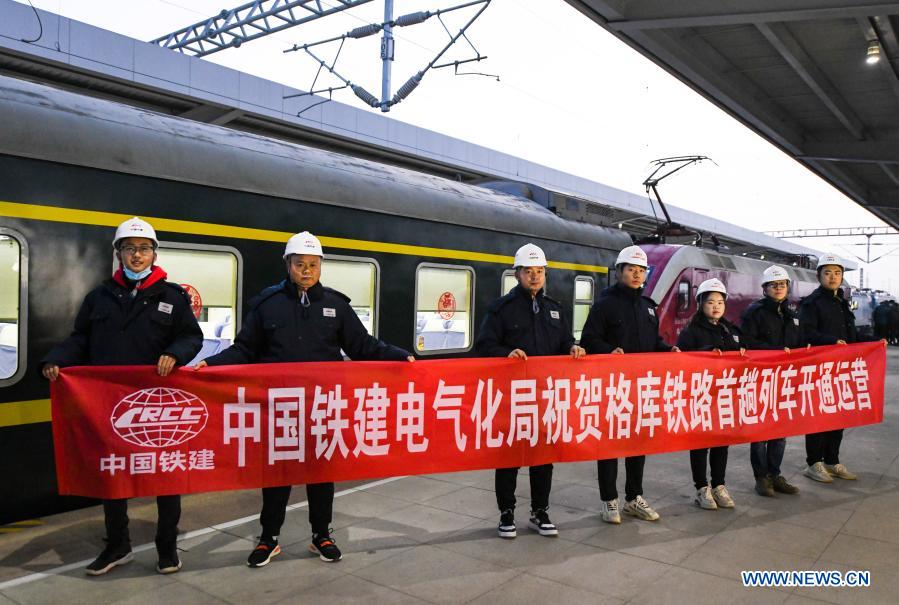 Railway constructors pose for group photo in front of train K9756 from Korla to Yetimbulak at the Korla railway station in Korla City of northwest China's Xinjiang Uygur Autonomous Region, Dec. 9, 2020. The train will run on the Xinjiang section of the Golmud-Korla railway. The 1,206 km Golmud-Korla railway linking Golmud City in Qinghai Province and Korla City in Xinjiang Uygur Autonomous Region, both in northwest China, was put into operation on Wednesday. The new rail artery, which will cut the travel time between Golmud and Korla from about 26 hours to roughly 12 hours, is the third railway line facilitating exchanges between Xinjiang and other regions. The line also connects with the Qinghai-Tibet Railway, the world's highest rail system, and the network as a whole will link Xinjiang, Qinghai and the Tibet Autonomous Region, facilitating exchanges in western China. (Xinhua/Wang Fei)