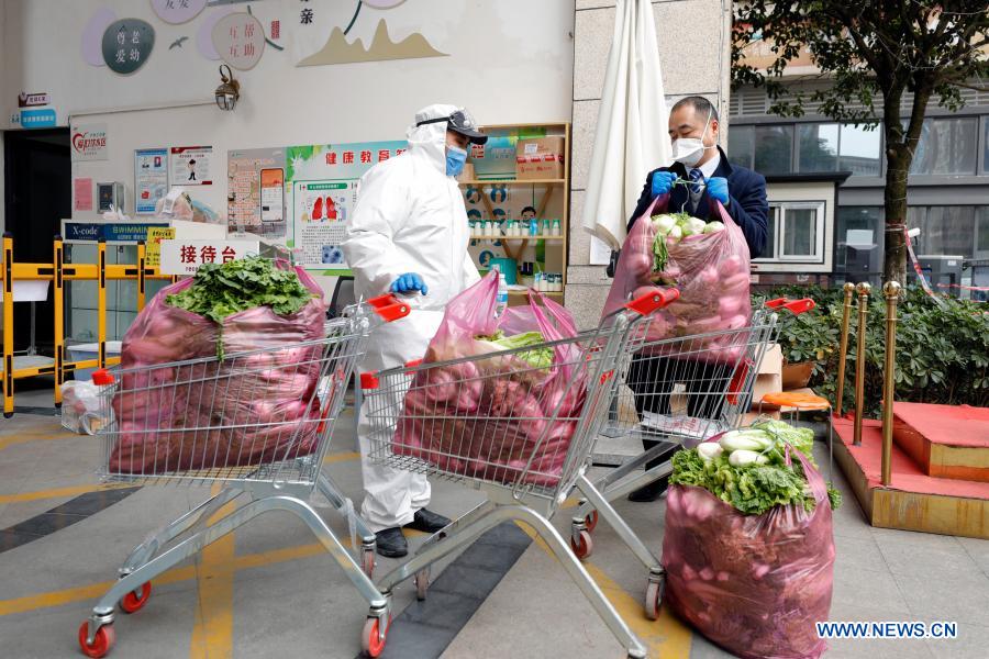 Property management staff load vegetables donated by warm-hearted citizens onto shopping trolleys before distributing them to residents in home quarantine at a community in Pidu District of Chengdu, southwest China's Sichuan Province, Dec. 11, 2020. By 6 p.m. Friday, Chengdu, capital of Sichuan Province, had reported 10 confirmed COVID-19 cases and two asymptomatic cases in the recent emergence of the epidemic, said Xie Qiang, director of the municipal health commission. Parts of a residential compound in Chengdu's Pidu District were classified as medium-risk areas for COVID-19 starting from 9 p.m. on Thursday. (Xinhua/Shen Bohan)