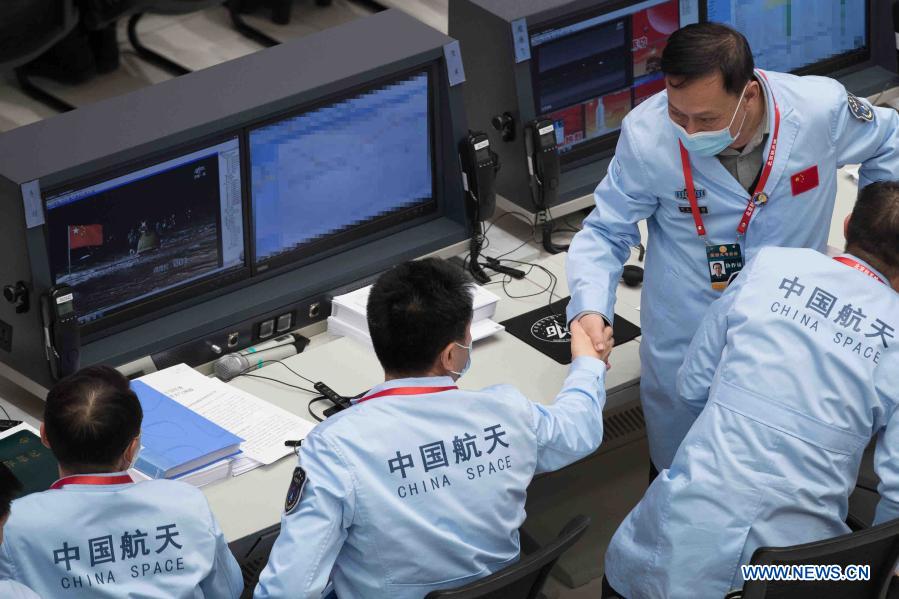 Technical personnel shake hands to celebrate the landing of the return capsule of China's Chang'e-5 probe at Beijing Aerospace Control Center in Beijing, capital of China, Dec. 17, 2020. The return capsule of China's Chang'e-5 probe touched down on Earth in the early hours of Thursday, bringing back the country's first samples collected from the moon, as well as the world's freshest lunar samples in over 40 years. (Xinhua/Jin Liwang)