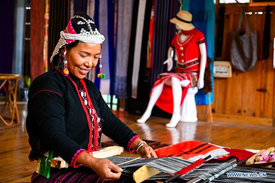 A villagers makes hand-woven brocade at the Ximeng Impression, a local ethnic cultural company, in Yangluo Village of Wa Autonomous County of Ximeng, southwest China's Yunnan Province, Dec. 20, 2020. In recent years, the local government of Wa Autonomous County of Ximeng has been enhancing the protection of local intangible cultural heritage and helping people of Wa ethnic group preserve and inherit their ancient cultures and traditions. Cultural companies including Ximeng Impression in Yangluo Village are also participating in the efforts. They provide the locals with opportunities of learning weaving techniques and selling products of a great variety of hand-woven clothing. (Xinhua/Wang Guansen)
