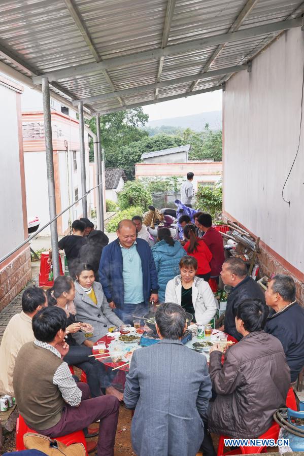 Villagers enjoy a meal together in Baorui Village, Qiongzhong County, south China's Hainan Province, Dec. 17, 2020. Visitors are likely to be impressed by brand-new residences and smooth paved roads when they come to Baorui Village in Hainan Province. But such a scene is barely imaginable back in 2017 when people of the Li ethnic group inhabiting here were mostly mired in poverty and lived in dilapidated houses. Back then, the village only had muddy paths with many places inaccessible even to motorcycle traffic. For a village which grows rubber trees as sole source of income, lack of decently paved roads had made it extremely difficult for villagers to transport and sell rubber. The year 2017 was a turning point for the villagers. In that year, thanks to a government-funded housing and infrastructure renovation plan, 62 households renovated their homes and 1.66 kilometers of roads were built. In the village, almost every family grows rubber trees for a living. To mobilize villagers, the local government bought them natural rubber price insurance to hedge against price risks. Some other impoverished villagers turned to raise farm animals as another way to cast off poverty. Only within years, the villagers here have access to tap water and natural gas, and they also have entertainment and sports facilities. All 167 residents of the 41 officially registered poor households shook off poverty by the end of 2018. (Xinhua/Zhang Liyun)