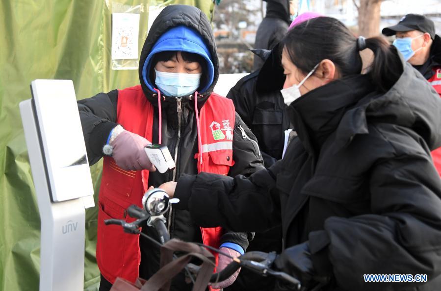 A community worker (L) measures body temperature for a resident at the entrance of the Hongcheng Huayuan residential compound on Wangquan Street, Shunyi District, Beijing, capital of China, on Dec. 29, 2020. Beijing reported seven new locally-transmitted confirmed COVID-19 cases on Monday, according to the Beijing municipal health commission. The seven patients, who live in the Shunyi District, are all close contacts of earlier reported cases. (Xinhua/Ren Chao)