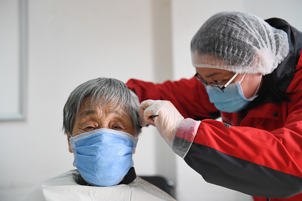  3月10日，北京市东城区海运仓社区社工任海燕为一位社区老人理发。