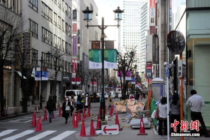 资料图:疫情下的日本东京街头,路面上挂着东京奥运的旗帜。中新社记者 吕少威 摄