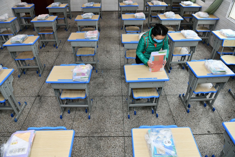 3月15日,在贵阳市云岩区第一小学初三年级集中教学点,老师为学生摆放和整理新课本。 新华社 图