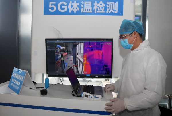 2月13日,在广西南宁东站,工作人员运用5G体温检测系统对进站旅客进行测温。(新华社)