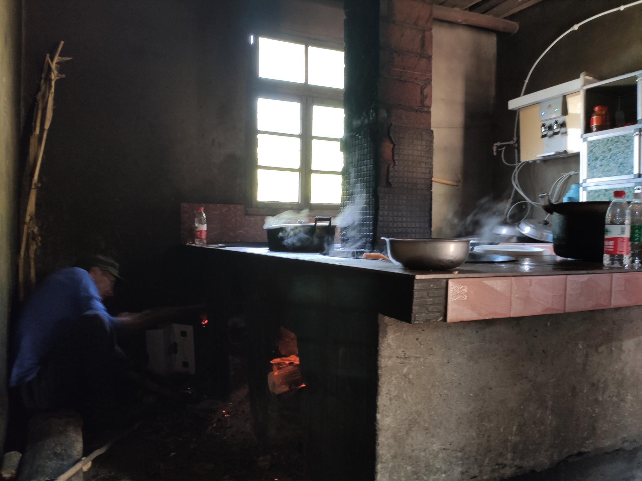 4月4日，村民在冯才勇家厨房帮忙烧饭。因电费贵，柳树桩基本家家户户都烧柴火