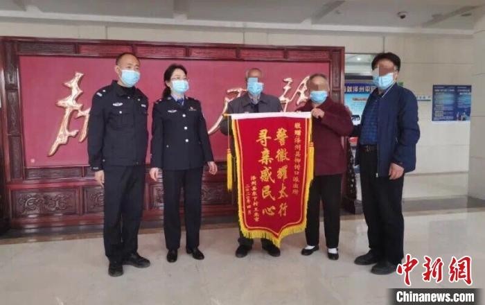钱某夫妇带着儿子到泽州县公安局,向帮助他们寻找到亲人的柳树口派出所和刑侦大队民警们送去锦旗。晋城市公安局供图