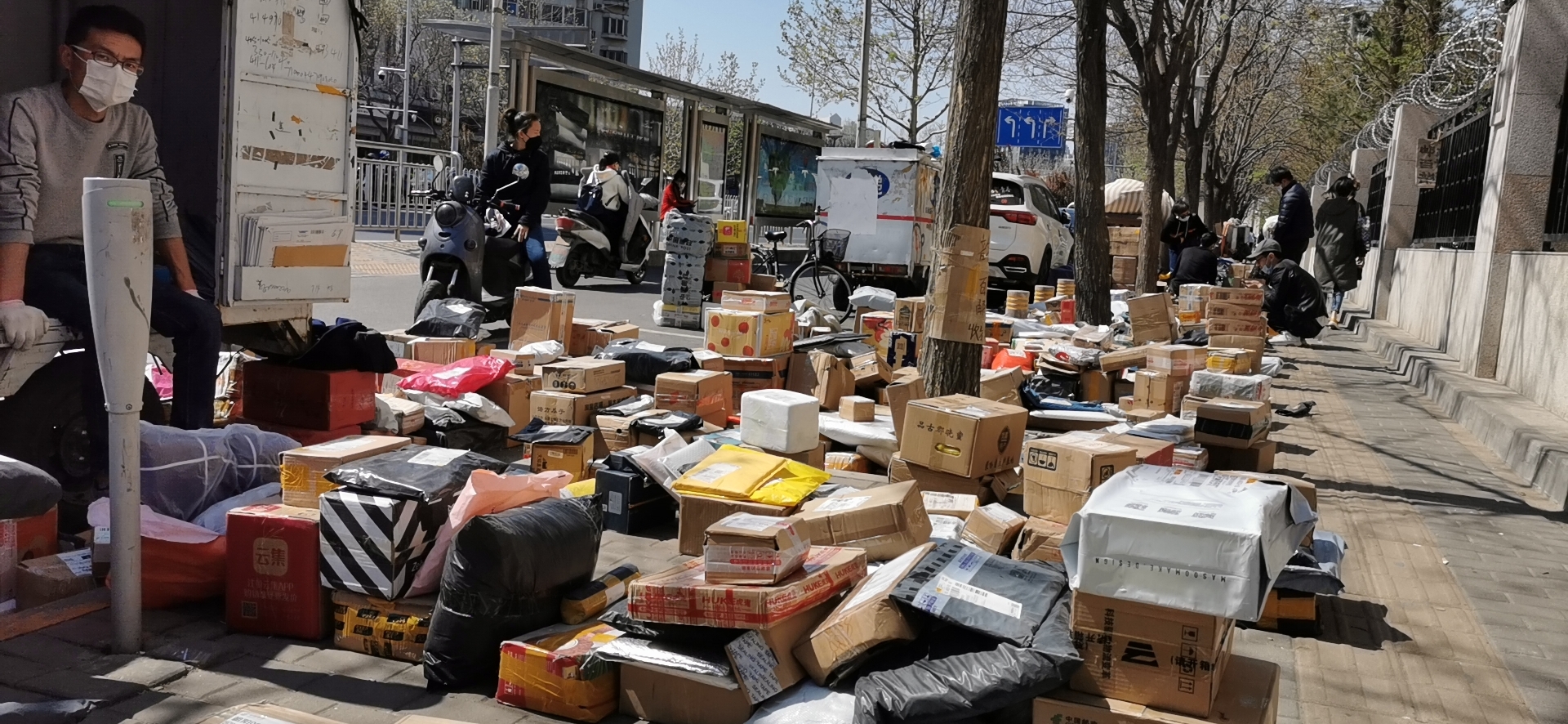 4月11日,朝阳区望京西园三区西门,各家快递公司的包裹摆满地,在人行道上延伸出去几十米。摄影/新京报记者 陈琳