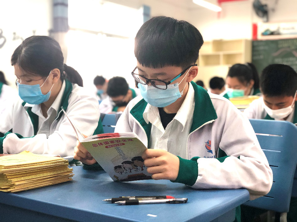 ▲学生认真阅读《总体国家安全观(海南省学生读本)宣传手册》