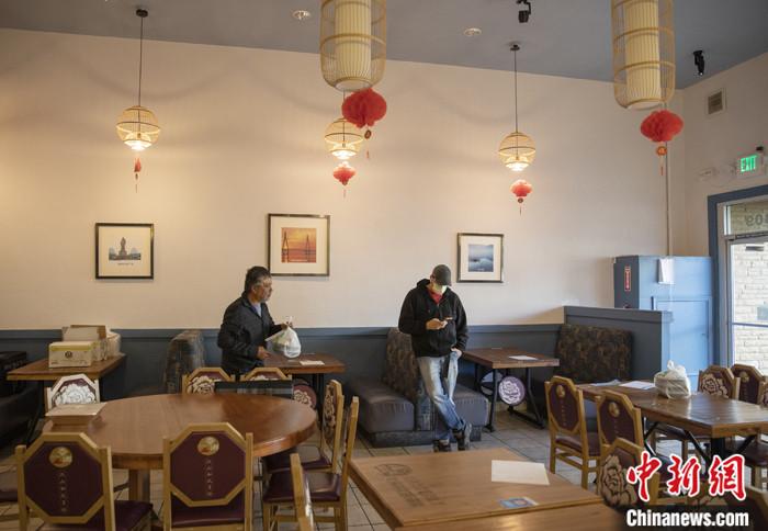 当地时间3月16日,一名戴口罩的顾客在美国旧金山湾区米尔布雷一家餐馆等餐。这家菜馆从当日开始实行“无接触取餐”,顾客网上下单,到店自取食物,饭店也可提供送餐服务。中新社记者 刘关关 摄